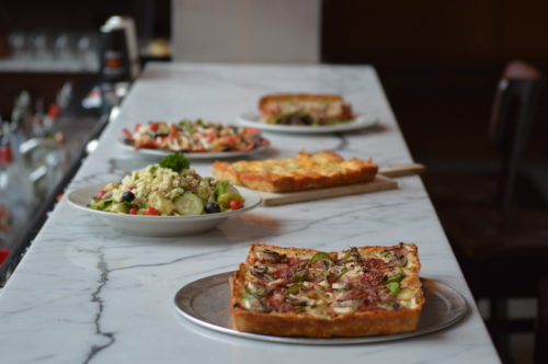 A spread of Shield's pizzas and fresh salads along the bar